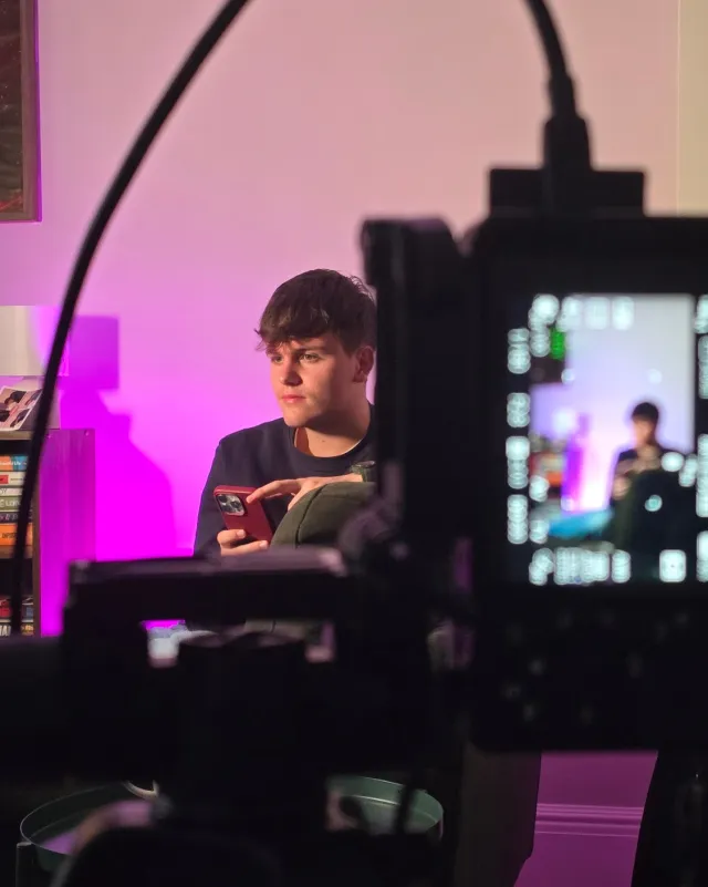 Austin behind the camera setting up a stream with pink lighting